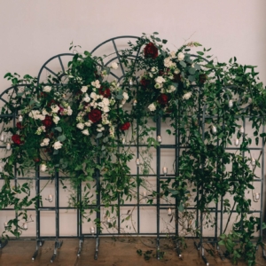 big beautiful asymmetric flower backdrop at wedding ceremony for lesbian wedding in new orleans decorated with white ivory and burgundy flowers and lots of greenery and foliage by kim starr wise