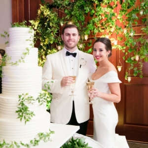 Kim starr wise floral event designer decorates wedding cake table and backdrop with vines and lush greenery