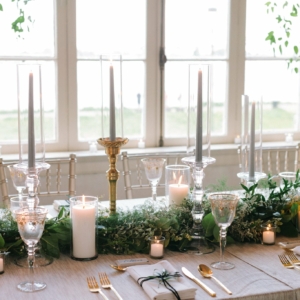 wide and tall centerpieces and table garland at wedding reception of foliage garland with white floral accents by kim starr wise