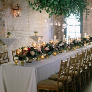 suspended greenery installation above head table at wedding ceremony with hanging globes and votive candles with dark moody floral accents created by new orleans event florist kim starr wise