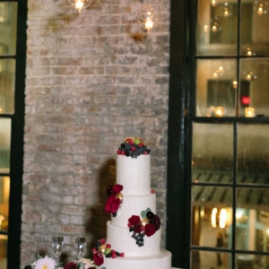 wedding cake by gambino's in new orleans louisiana decorated with gold painted figs, dahlias, black berries, raspberries, coordinating floral, greenery, fruit by kim starr wise floral events