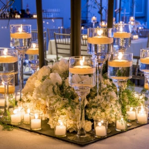 elegant wedding florals for january wedding in new orleans louisiana event florals by kim starr wise created dreamy romantic wedding reception dense florals on mirrored base with votives and floating candles at the base of large tree floral centerpiece installations