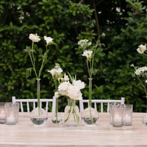 Pub table centerpieces at wedding reception in new orleans all pub tables had a collection of small bud vases in shades of white incorporating florals displayed in thin clear glass bud vases of varying heights by master wedding event florist kim starr wise