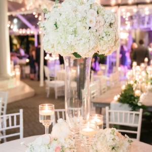 Centerpieces at outdoor wedding reception were repurposed from the aisle decor at the wedding ceremony large and medium white and ivory floral arrangements with garden roses, white hydrangea, ivory majolica spray roses, white polo roses by kim starr wise wedding and event florist