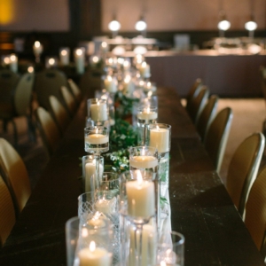 wedding reception seated dinner table decor with foliage and greenery with votive candles romanic including eucalyptus, magnolias, olive, smilax, ruscus, and small white flowers