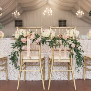 Wedding ceremony had a seated dinner, and the bride and groom's chairs were decorated with florals and greenery