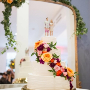 wedding cake decor for tiered cake decorated with diagonal cascade of vibrant flowers roses dahlias greenery by kim starr wise floral events in new orleans