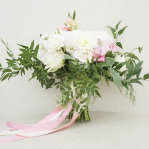 medium-sized cascading bridal bouquet in shades of green, blush, ivory, grey, mauve using peonies, lambs ear, ranunculus, dahlias, seeded eucalyptus, faith roses, garden roses and spray roses with ribbons and bows to create mixed texture finish designed and created by event florist kim starr wise for november wedding ceremony in new orleans