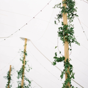 wedding reception tent poles decorated with smilax vines at mississippi gulf coast wedding in october by kim starr wise floral events