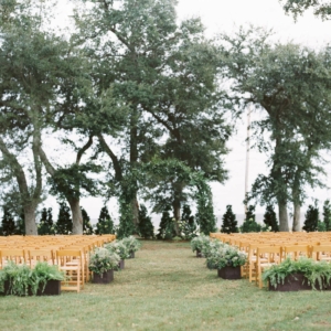 wedding ceremony flowers with arch decor and chair markers with greenery overlooking mississippi gulf coast october wedding florals kim starr wise