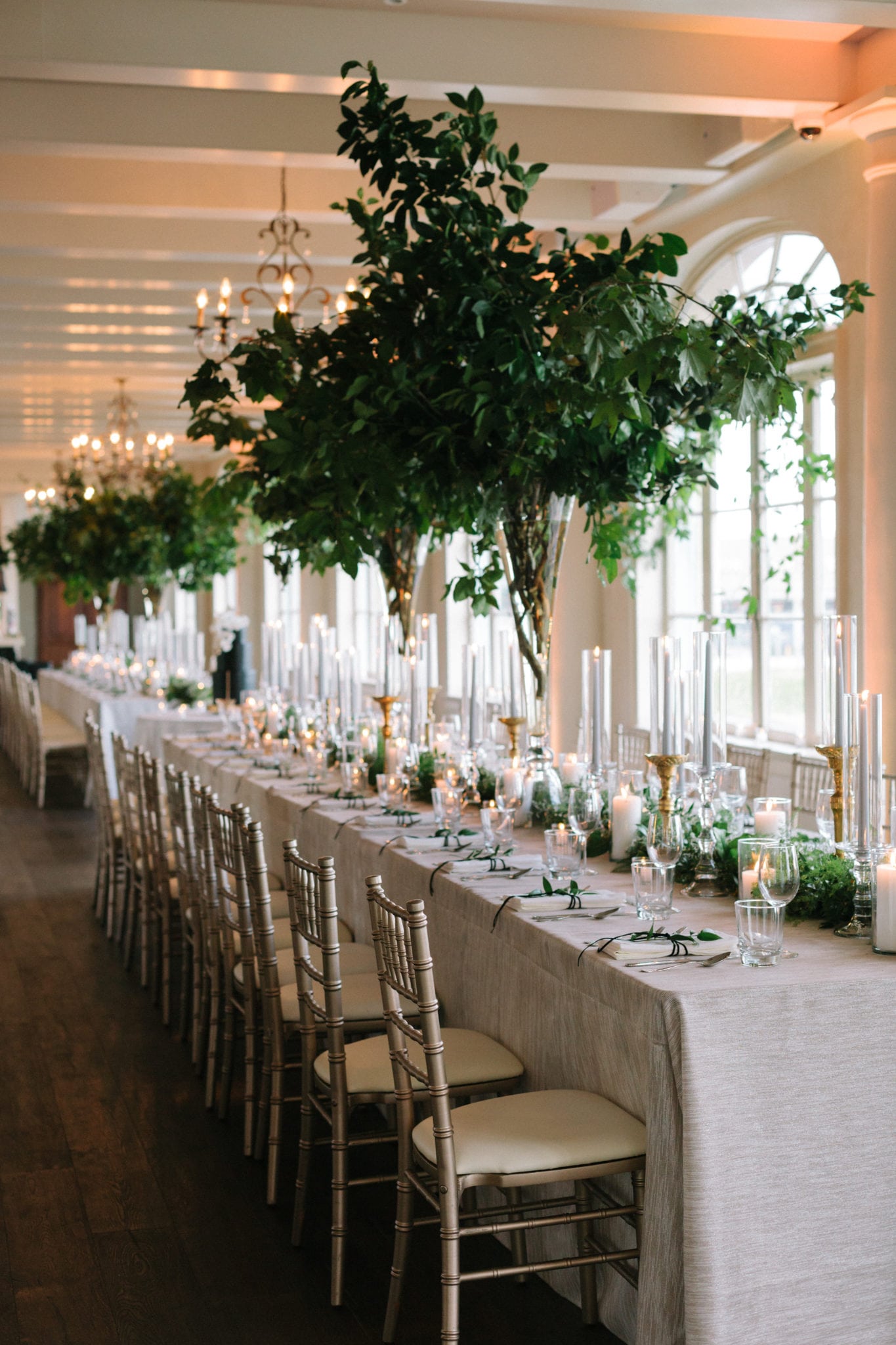 wide and tall centerpieces and table garland at wedding reception of foliage garland with white floral accents by kim starr wise
