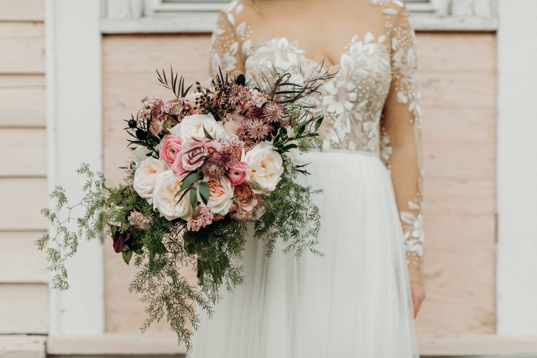 wild and asymmetric bridal bouquet with lots of movement and color palette to be pale pink mauve and green with touches of black flowers of scabiosa, ranunculus, roses, ruscus, thistle, and seasonal blooms and greenery for winter wedding in new orleans french quarter by kim starr wise wedding and event florist